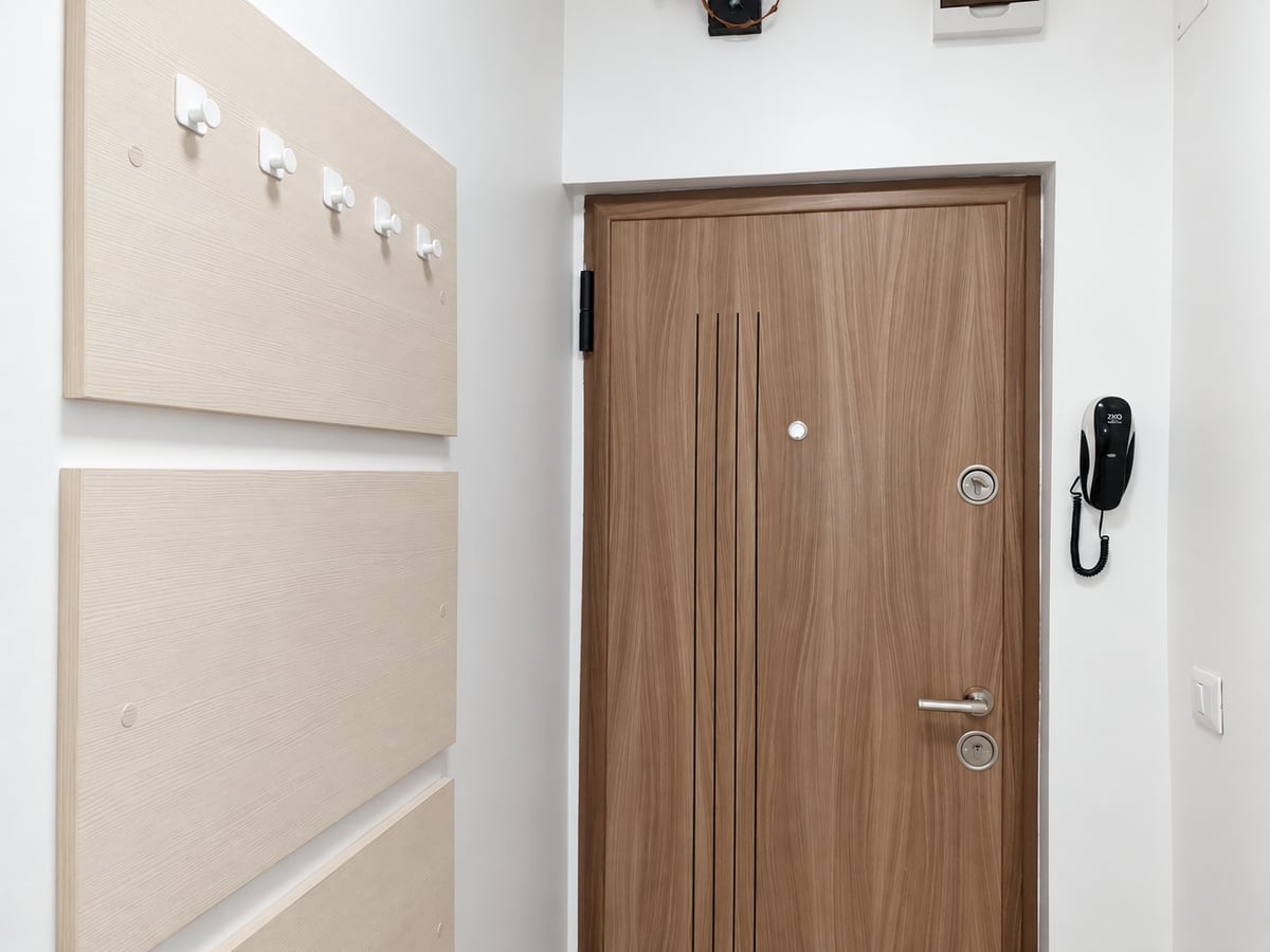 The entrance: a run of pale panels with a row of hooks, the timber front door and the entryphone.