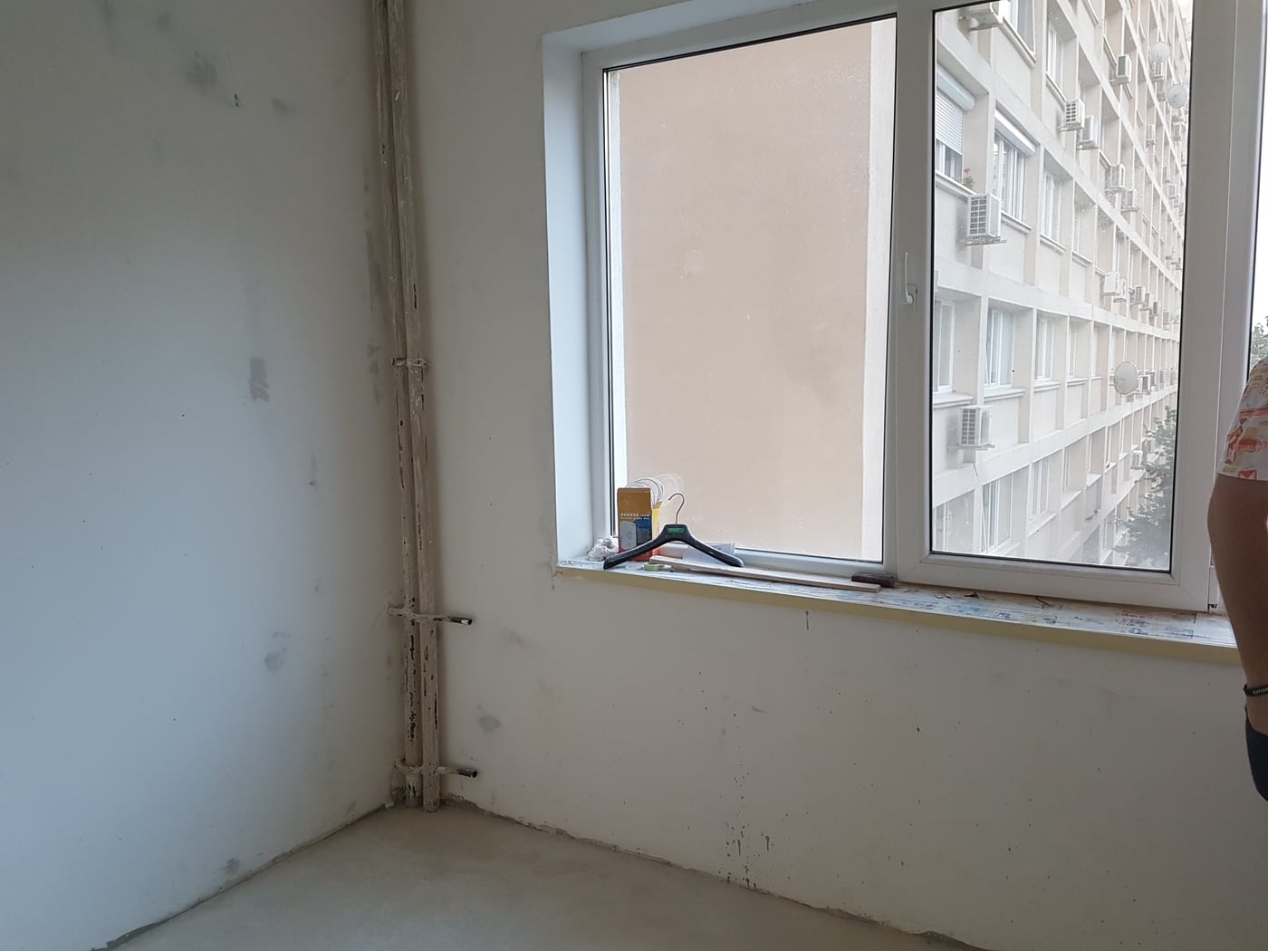 The same room during the works: bare plastered walls, an unfinished window reveal and the block opposite visible through the glass.
